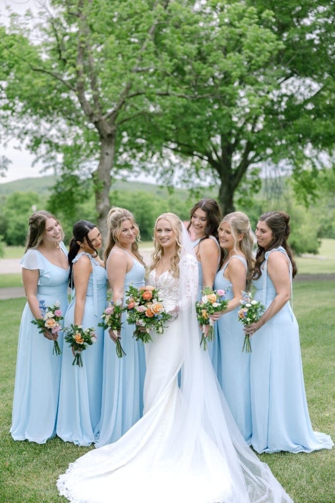 bride poses for photos at her wedding with her bridesmaids in front of ravenswood mansion in Franklin, TN with her gorgeous bouquet from larson's floral co