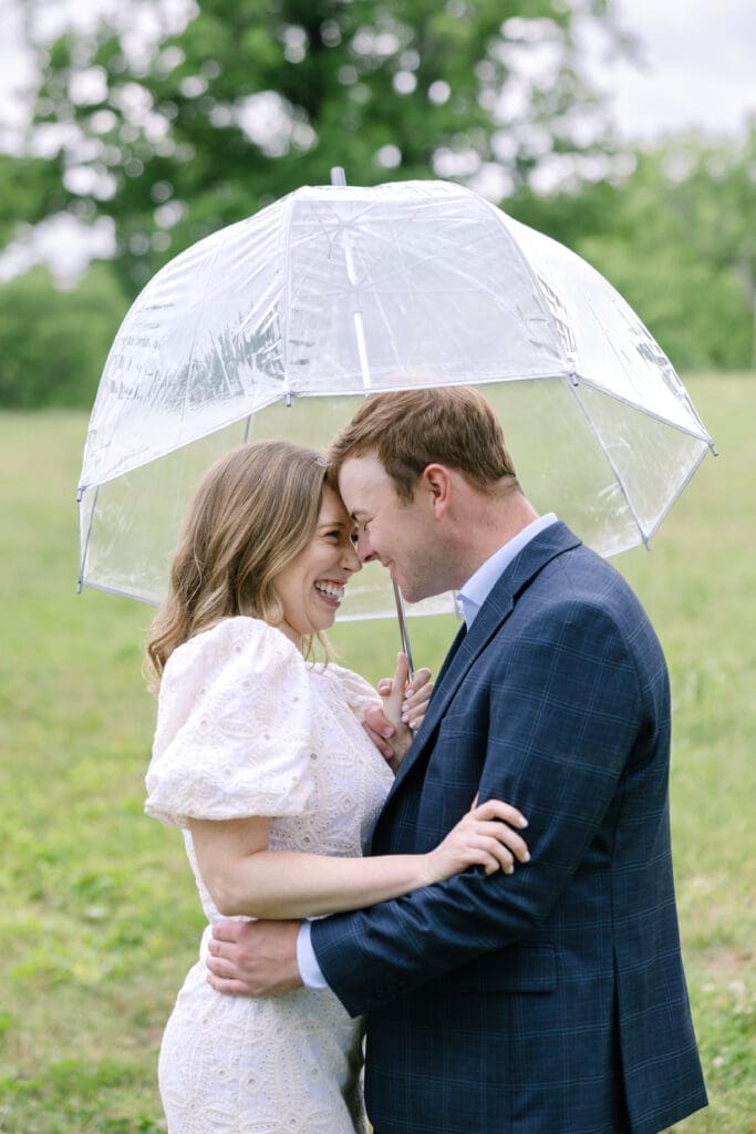 Tender forehead touch moment between engaged couple under an umbrella during outdoor Nashville engagement photos