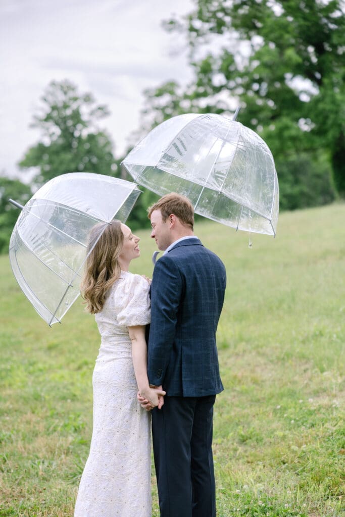 Couple holding clear umbrellas during outdoor spring engagement session in Nashville TN