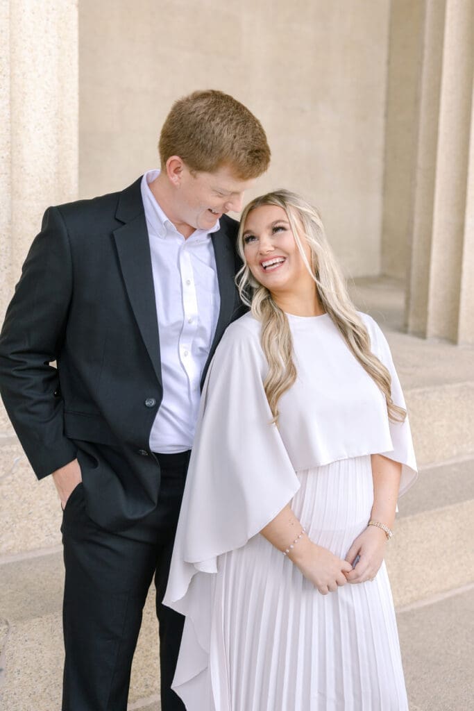 Engaged couple laughing together on the steps of the Parthenon in Centennial Park Nashville
