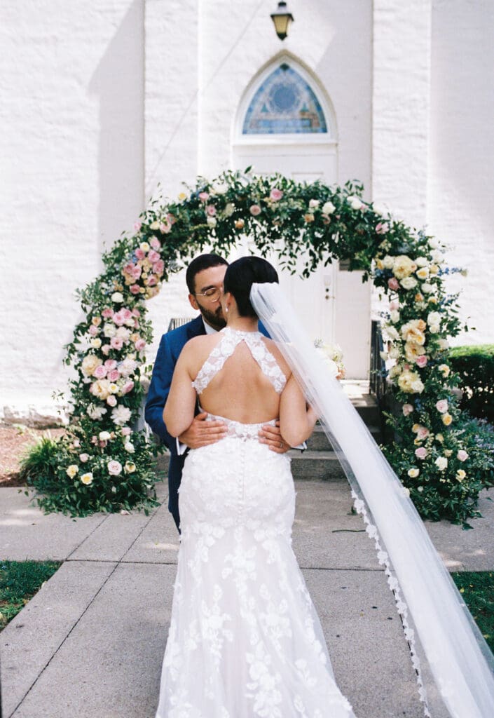 bride and groom pose in front of beautiful floral arch by Tulia Grace Florals in franklin, tn